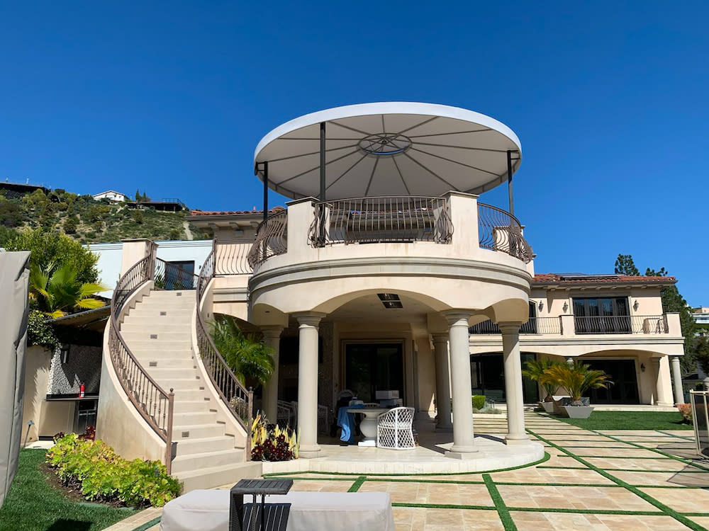 exterior of white home with a route patio with custom shade structure