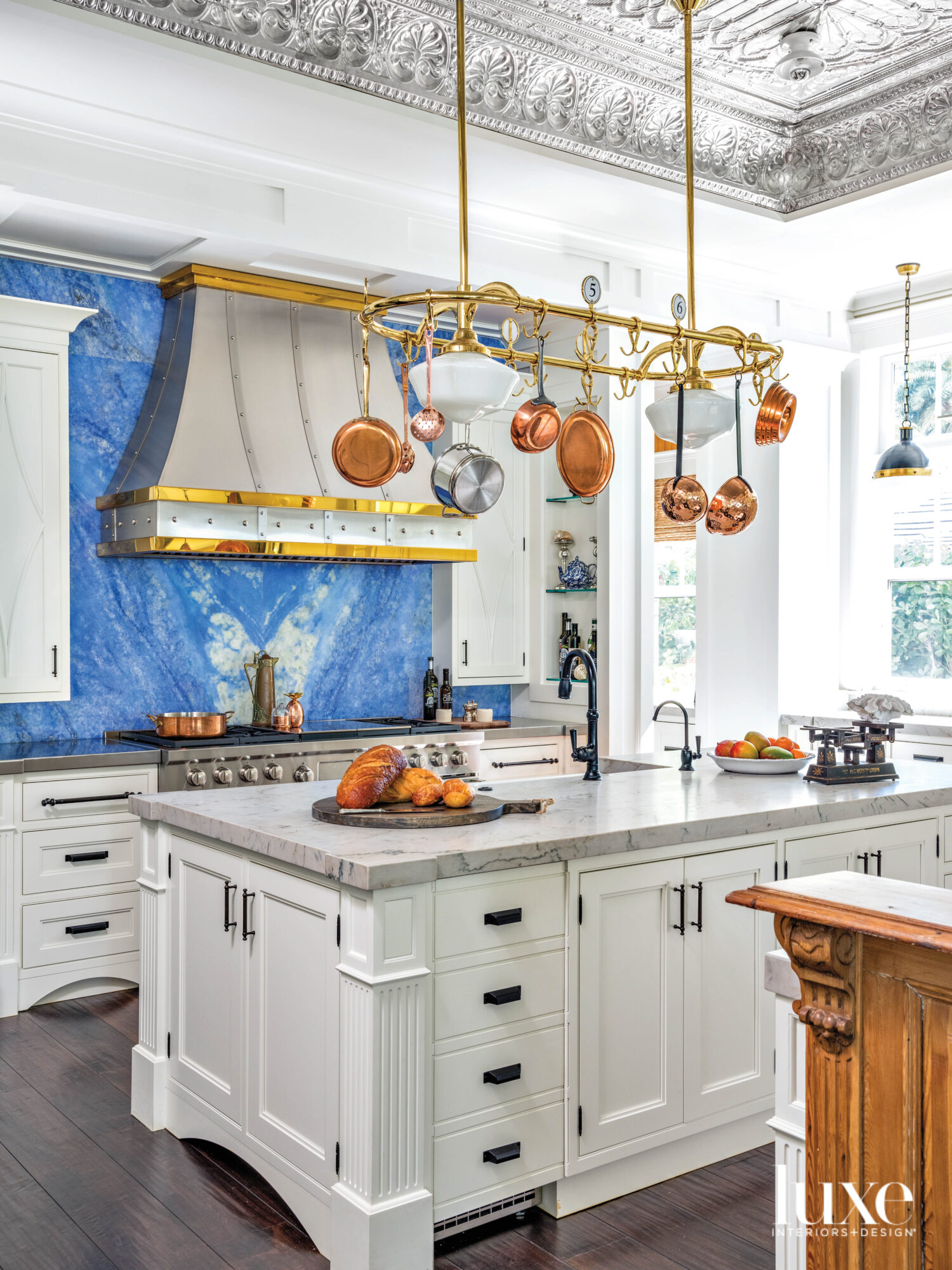 kitchen with tin ceiling, a blue quartz backsplash, hanging copper pots and an island