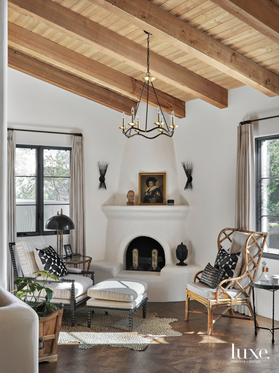 A sitting area in the master bedroom includes a rounded-out fireplace, a funky rug and two different yet complementary chairs.