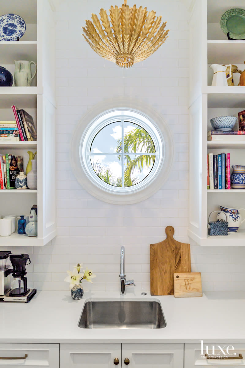 butlers pantry with porthole window, white quartz countertop and subway tile-clad walls