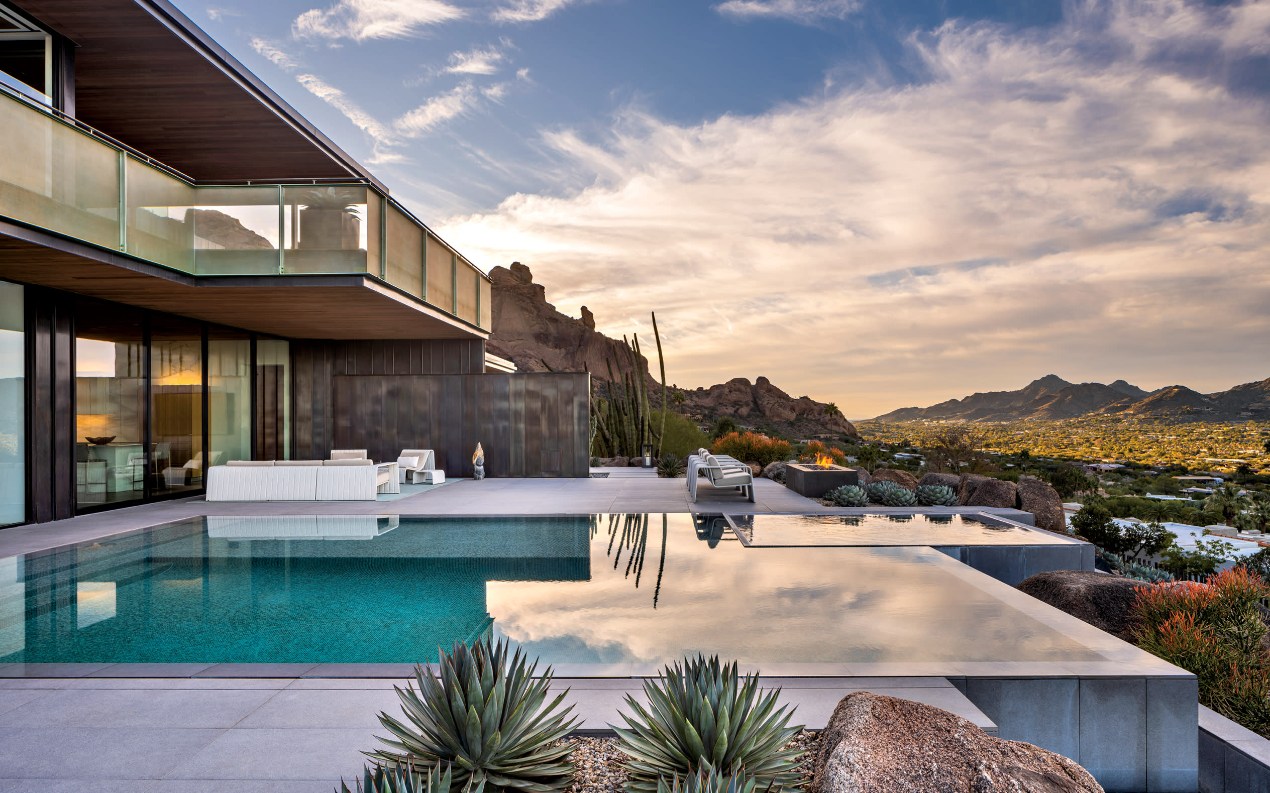 infinity pool along a luxury contemporary home with views of the Arizona mountains beyond