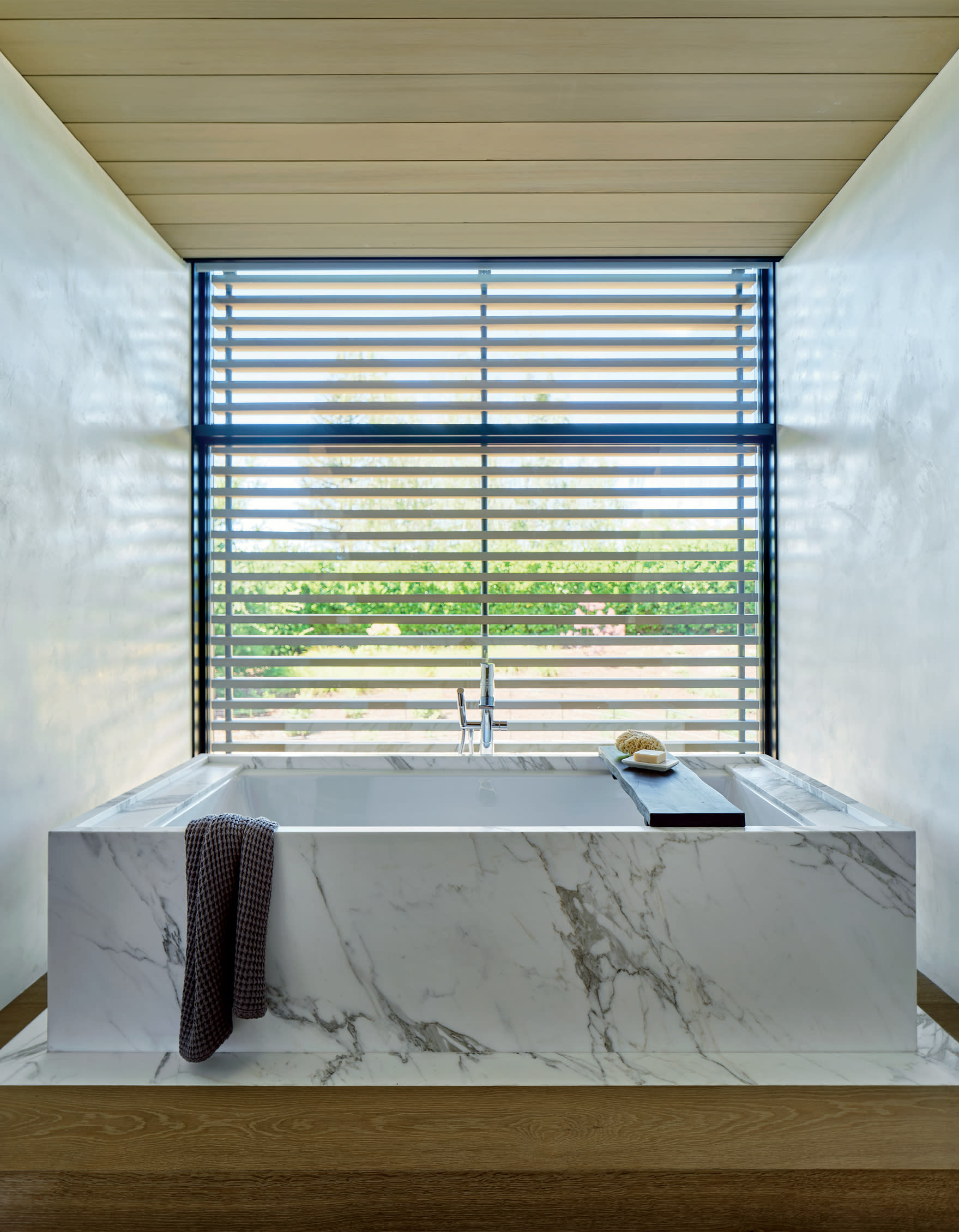 primary bathroom with Calacatta Oro marble-clad soaking tub on oak-and-marble pedestal 