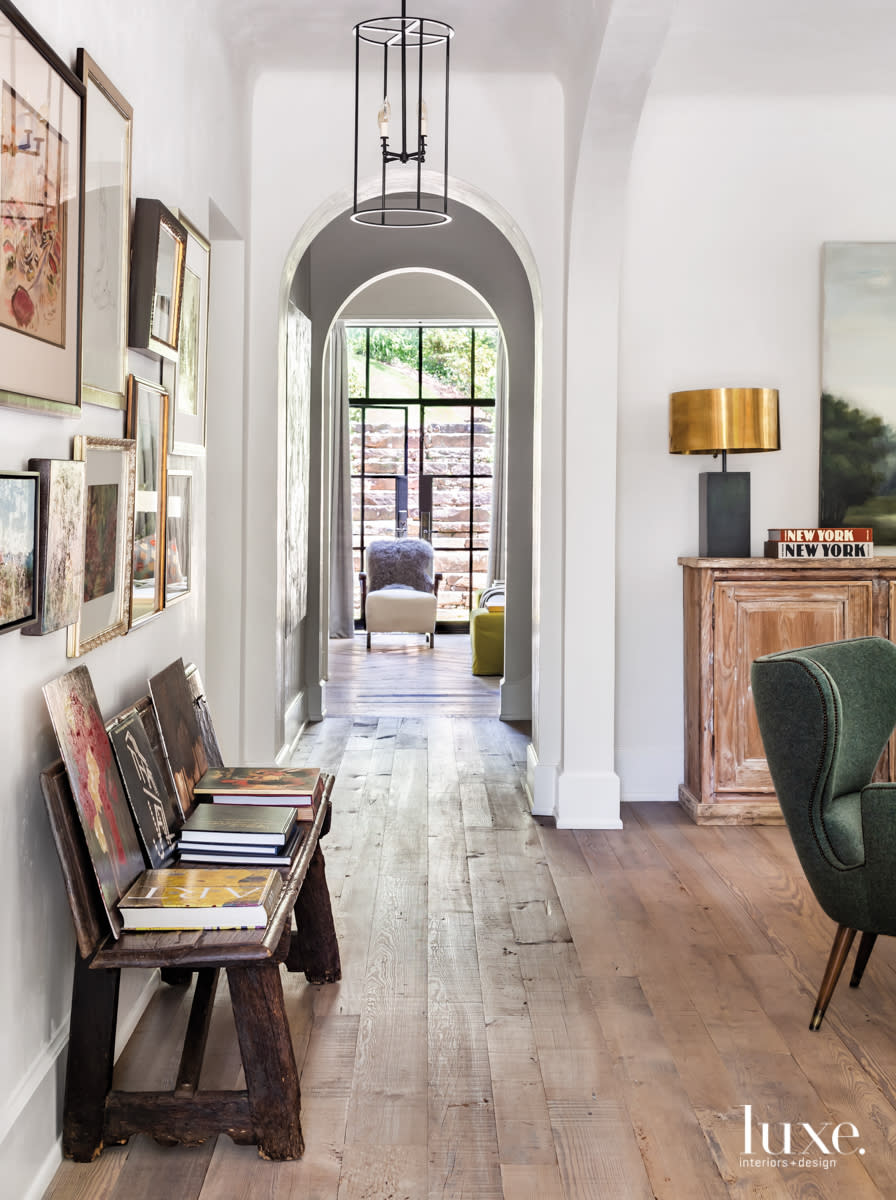 entryway with curved door, rustic bench and arrangement of wall art