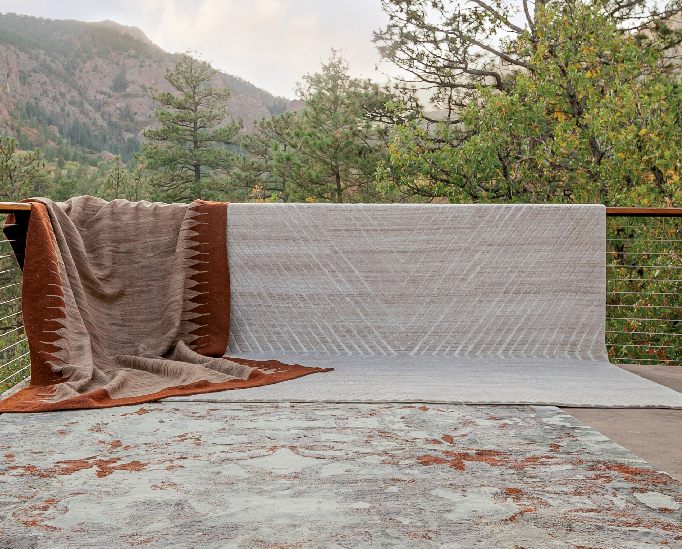 two blankets draped over a porch railing in the mountains