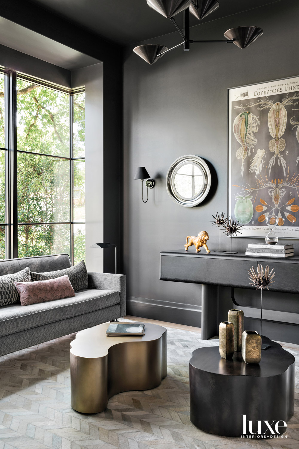 Sitting room with dark gray walls, metallic cocktail tables and large windows