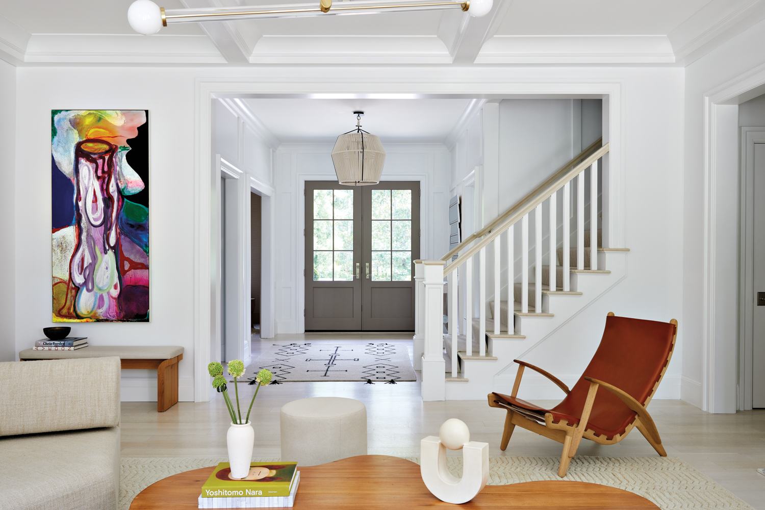 entryway with white stairs, red armchair, and doormat