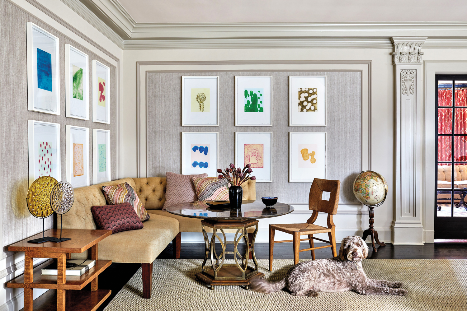 living room with colorful artwork, tan sectional, coffee table and fluffy dog in home by Teresa Manns