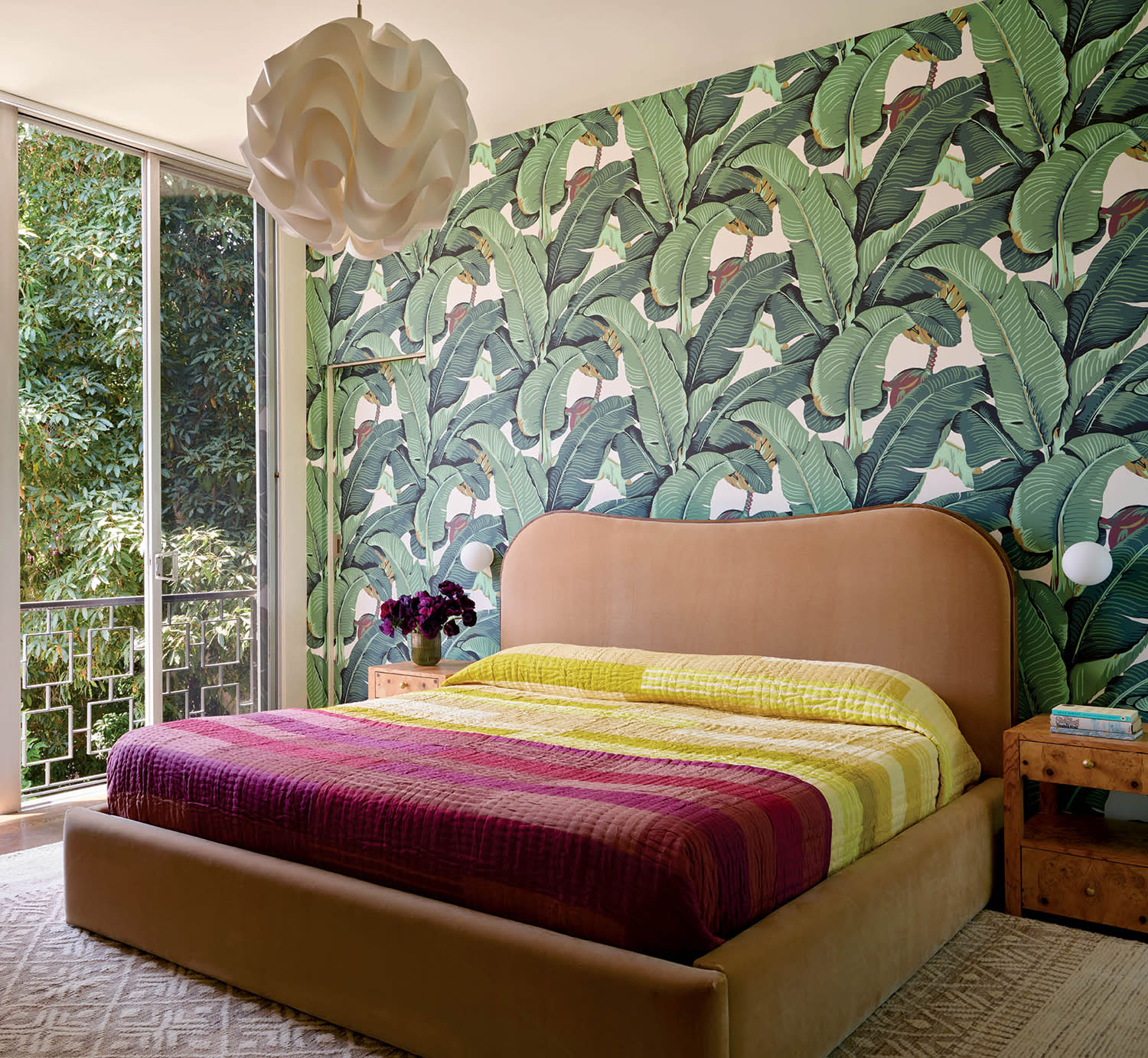 colorful midcentury bedroom with a leaf motif wallpaper and orange velvet bed