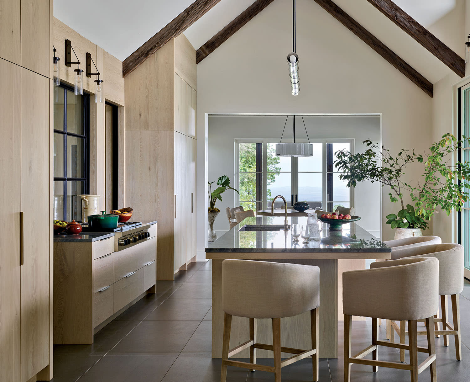 A kitchen with light wood cabinets and a kitchen island set with high-top chairs.