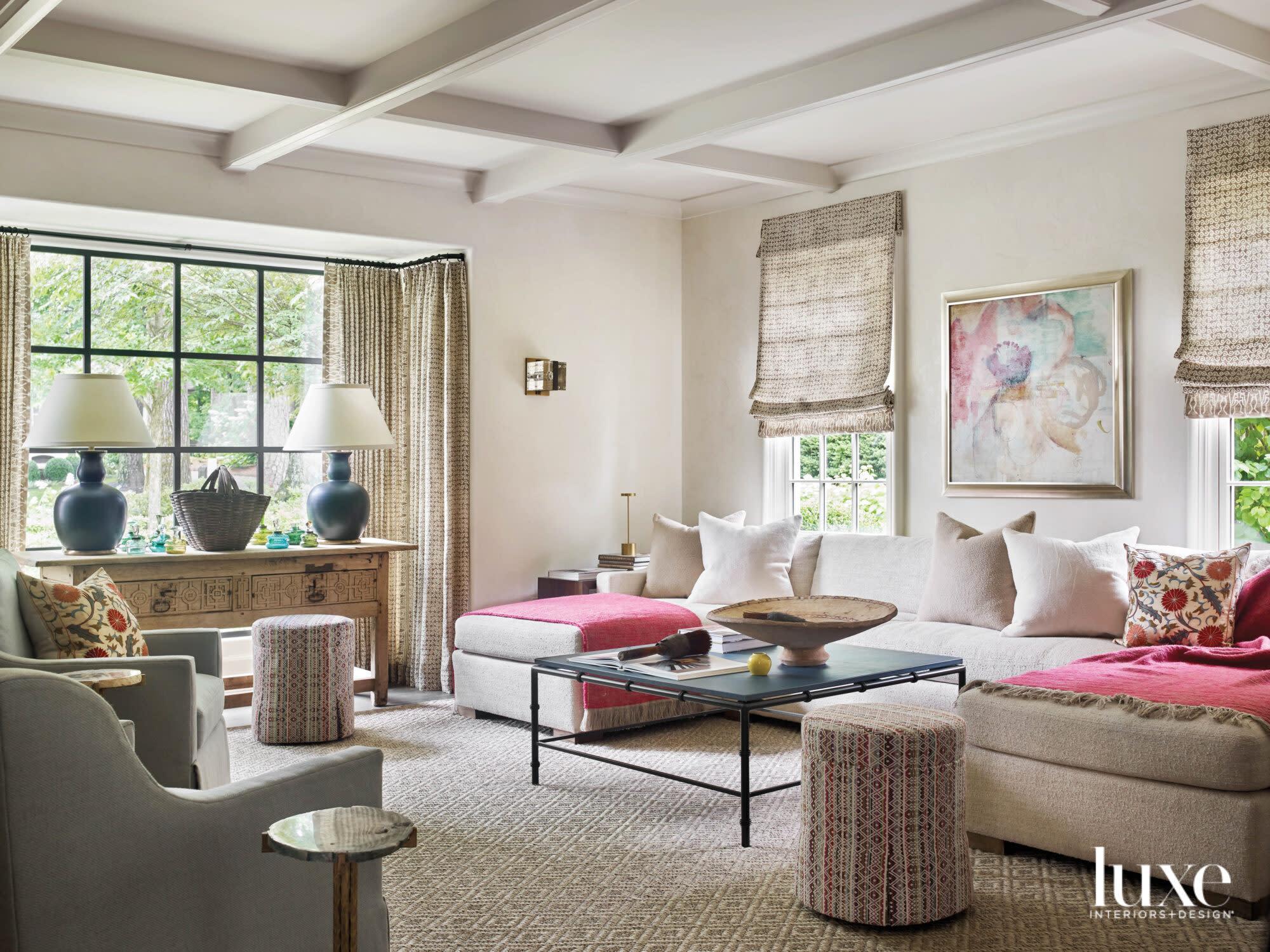 Large living room with decorative ceiling details, L-shaped sofa and bright pink throws