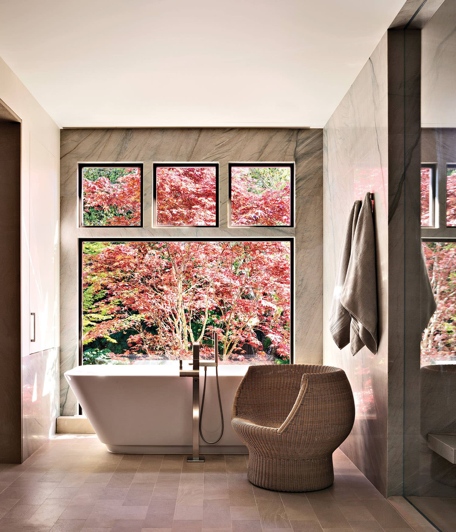 contemporary bathroom with a tub positioned in front of a window overlooking a Japanese maple