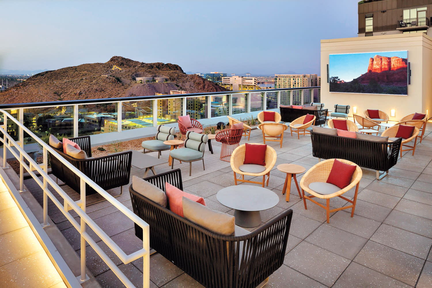 Rooftop lounge featuring woven and cushioned seating with desert mountain views.