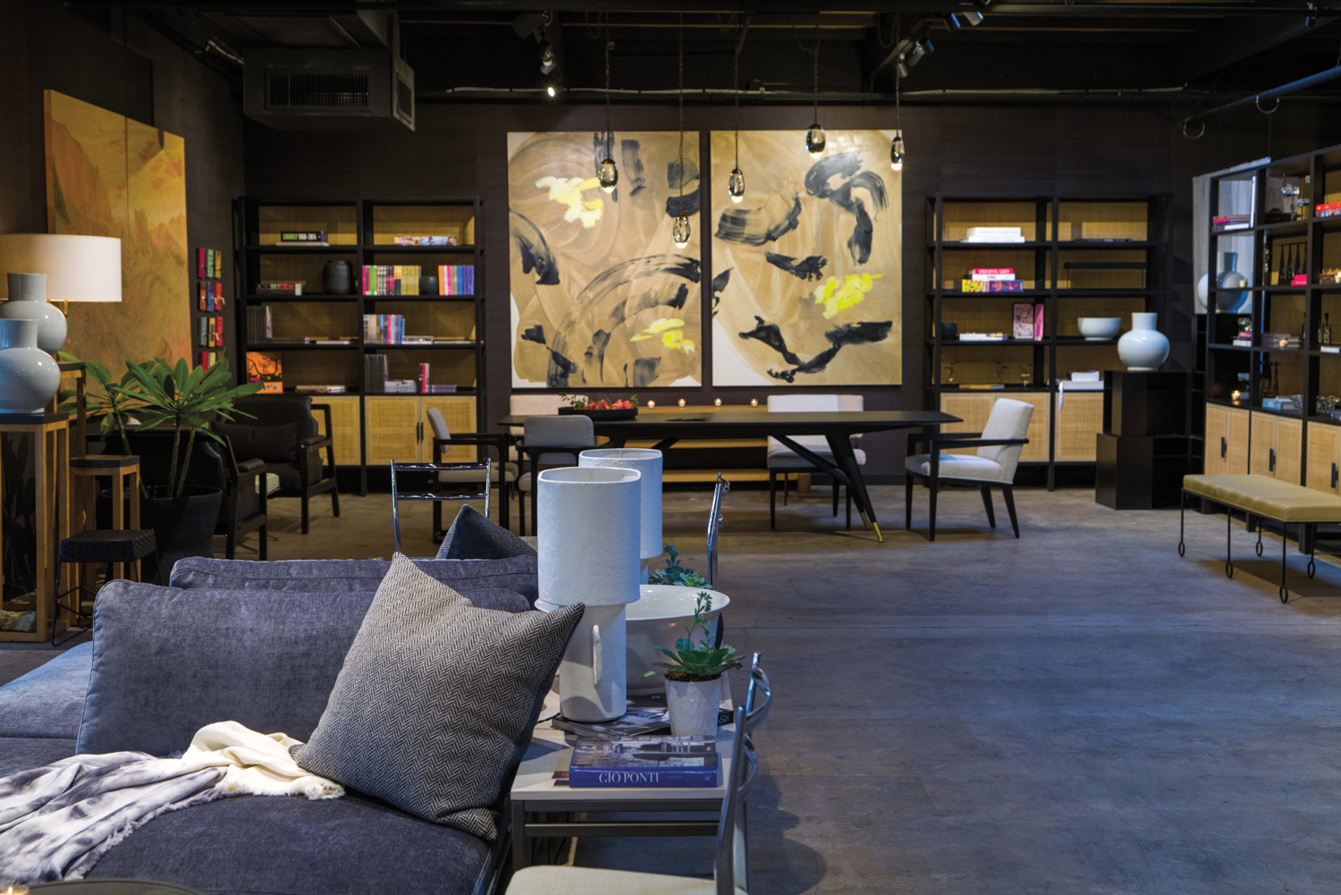 Showroom space with large black-and-gold artwork overlooking a black dining table.