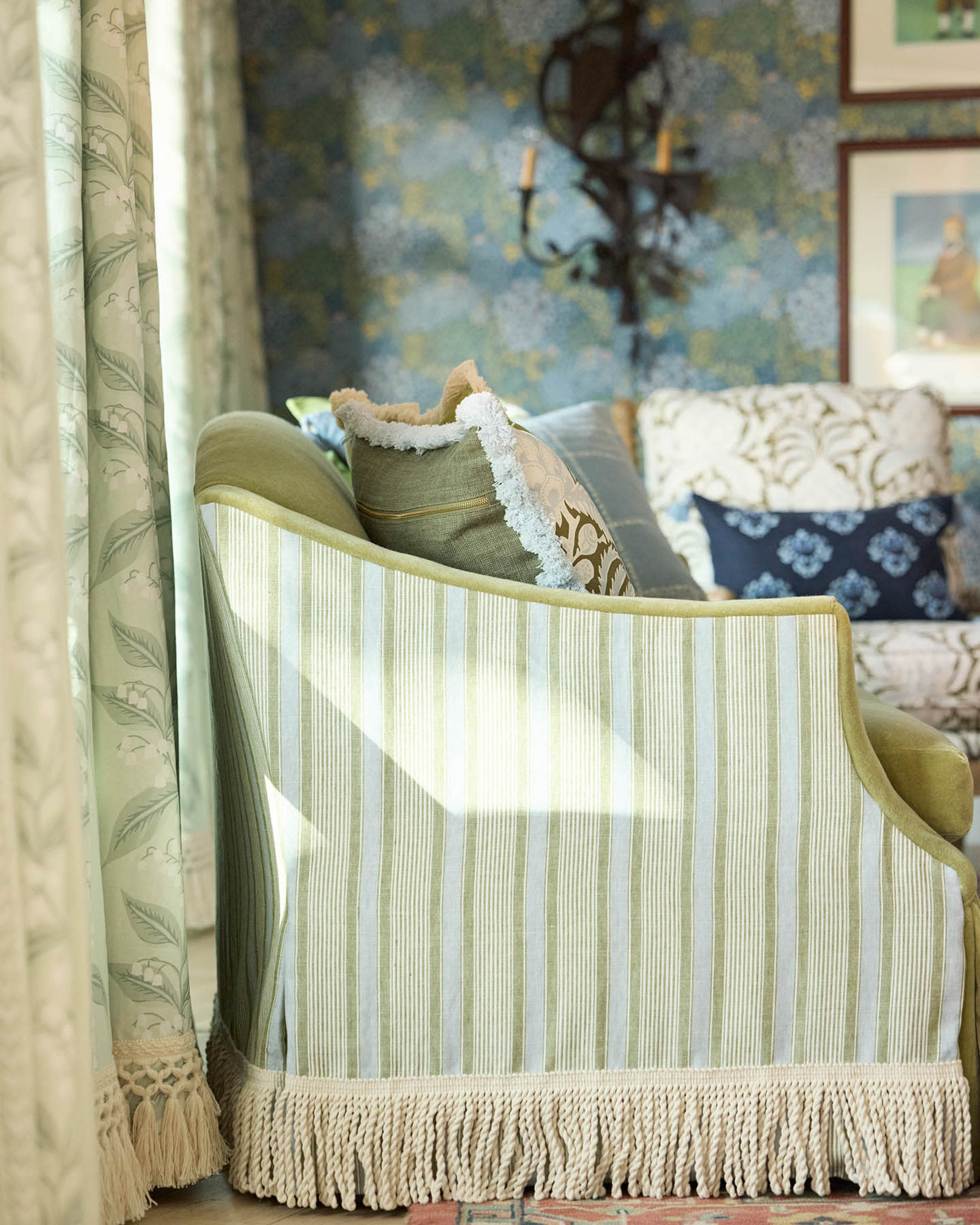 green sofa with a blue French stripe and a tasseled bottom edge