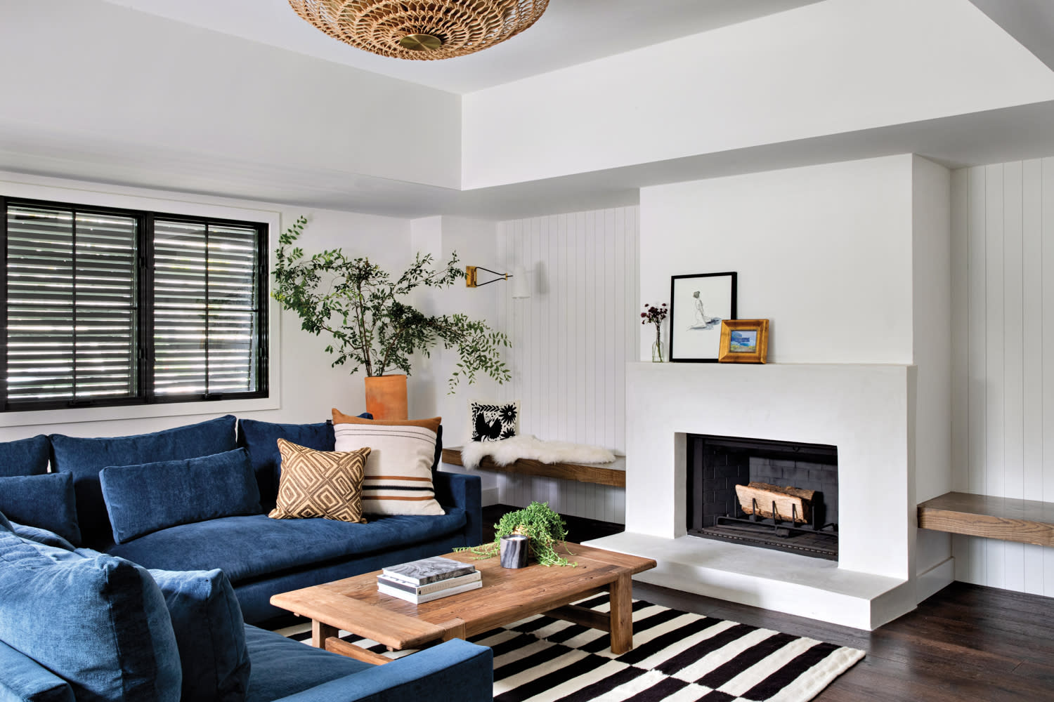 family room with blue sectional, black and white rug and fireplace, with a raffia pendant overhead