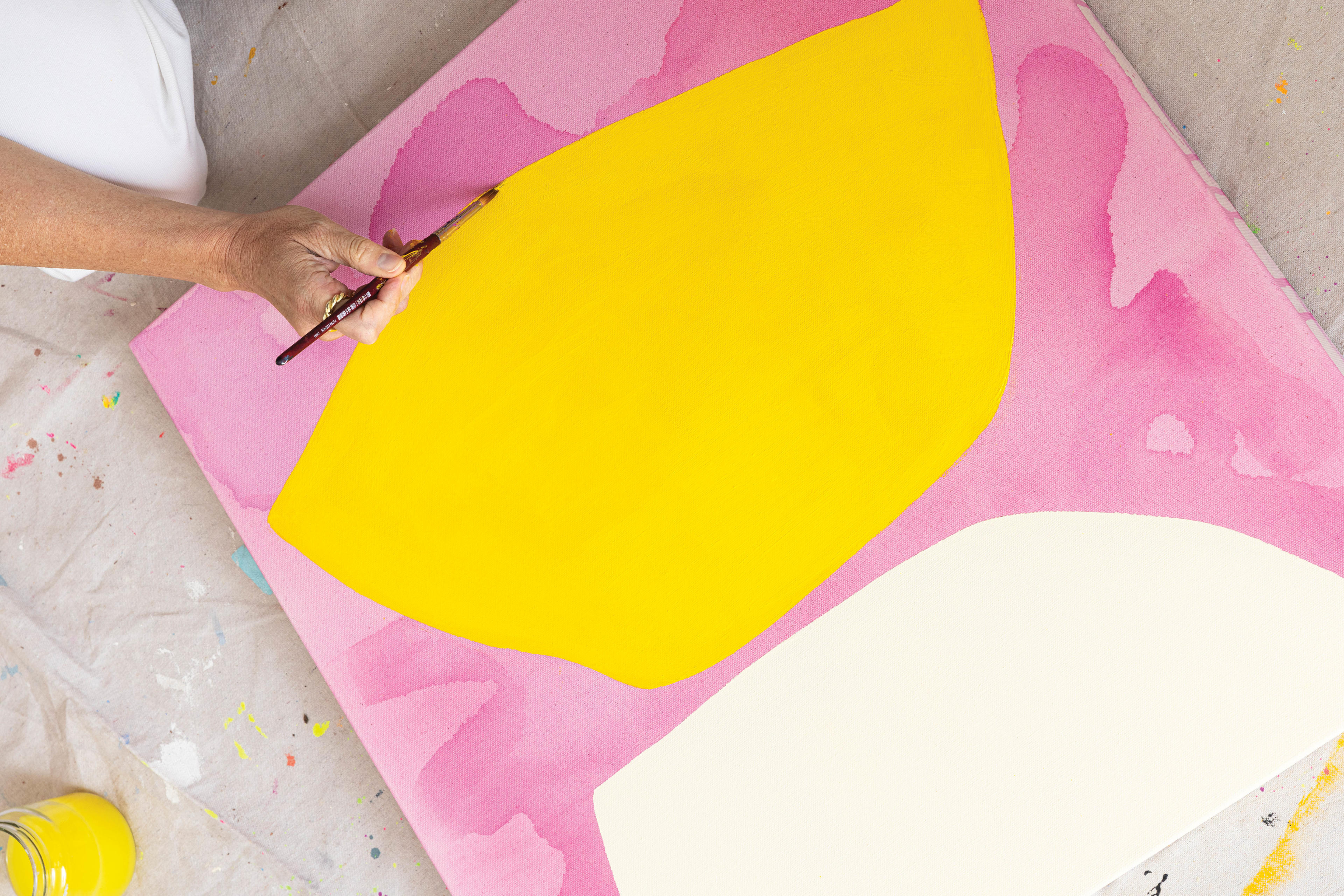 Mia Farrington works on a pink and yellow painting