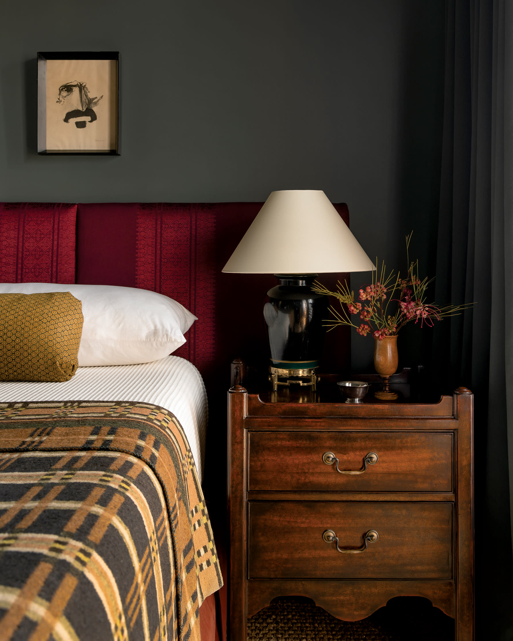 bedroom with green walls and a red upholstered headboard and a vintage nightstand