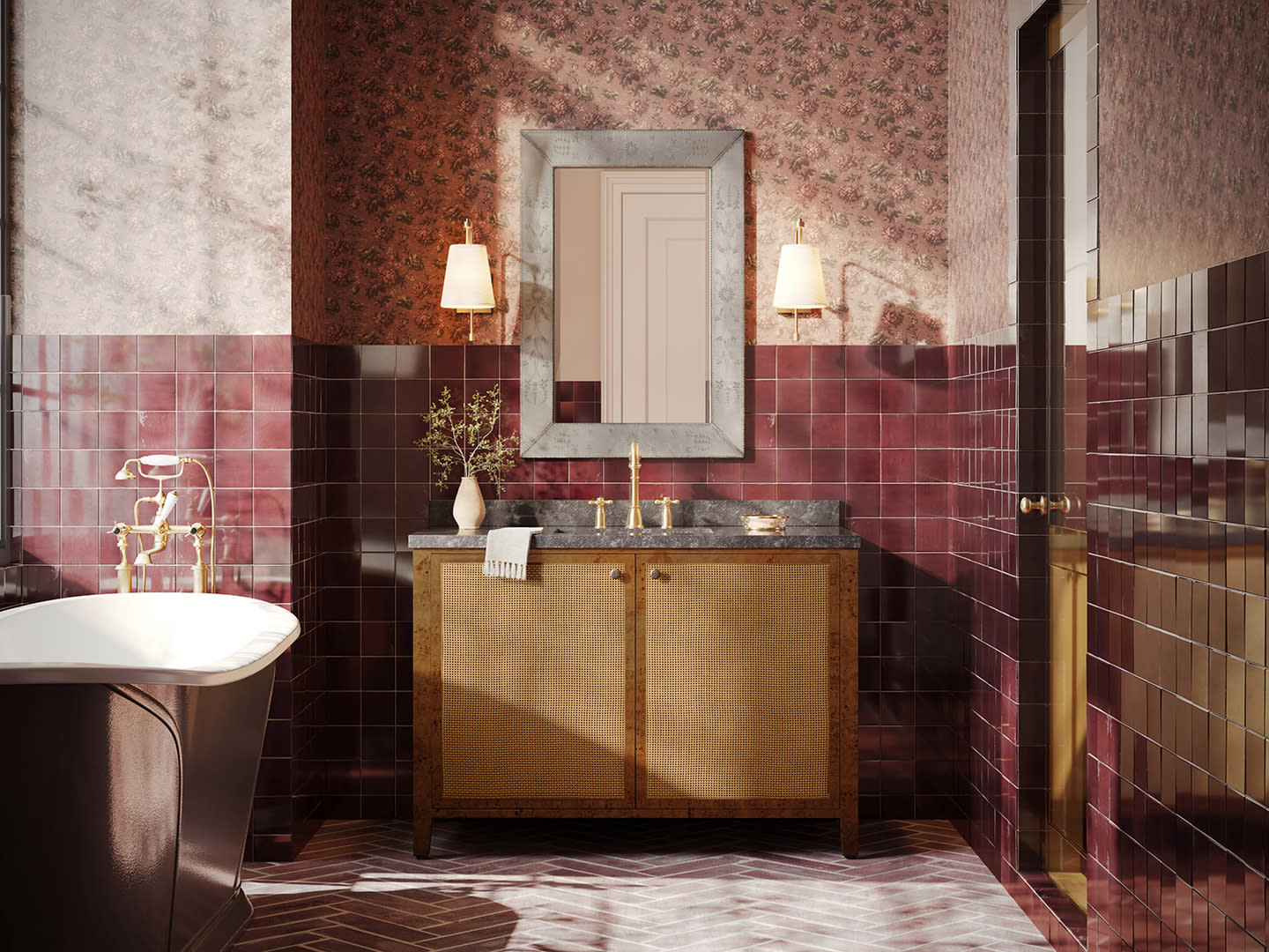 Elegant bathroom with maroon tiled walls, floral wallpaper, and a freestanding tub. A wicker cabinet with marble top and mirror sits below wall sconces.