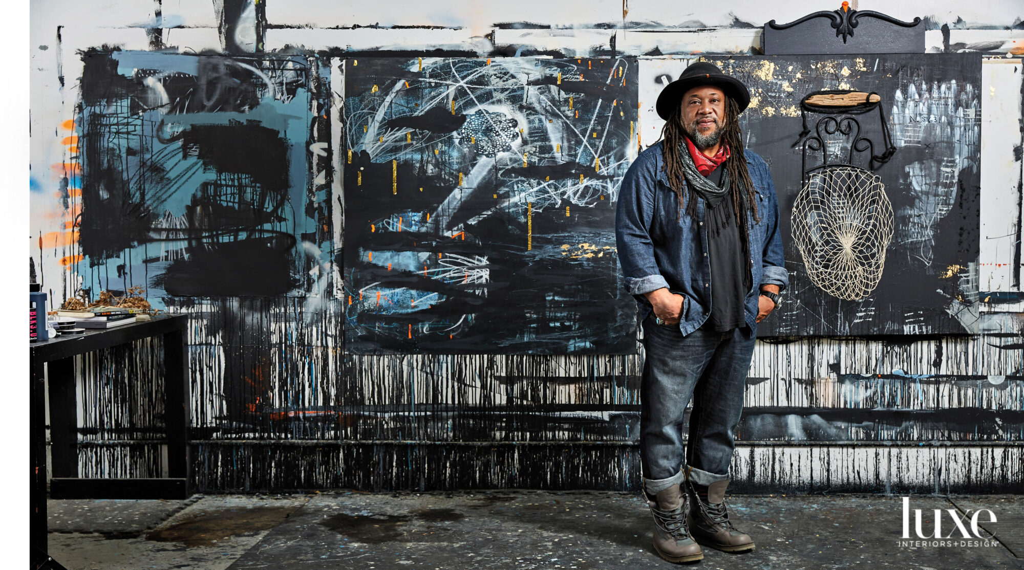 Portrait of a man with long hair in front of large, dark abstract painting