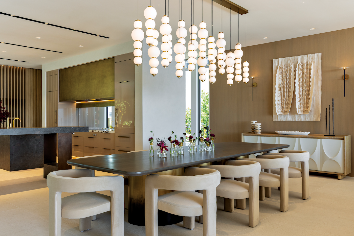 Dining and living area featuring sculptural chandeliers and contemporary artwork.