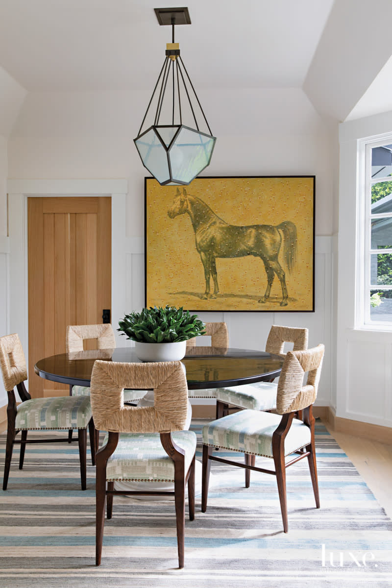 Breakfast room with horse painting on the wall and a round table.