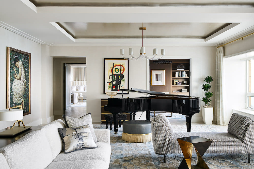 White sitting room with comfortable seating and grand piano.