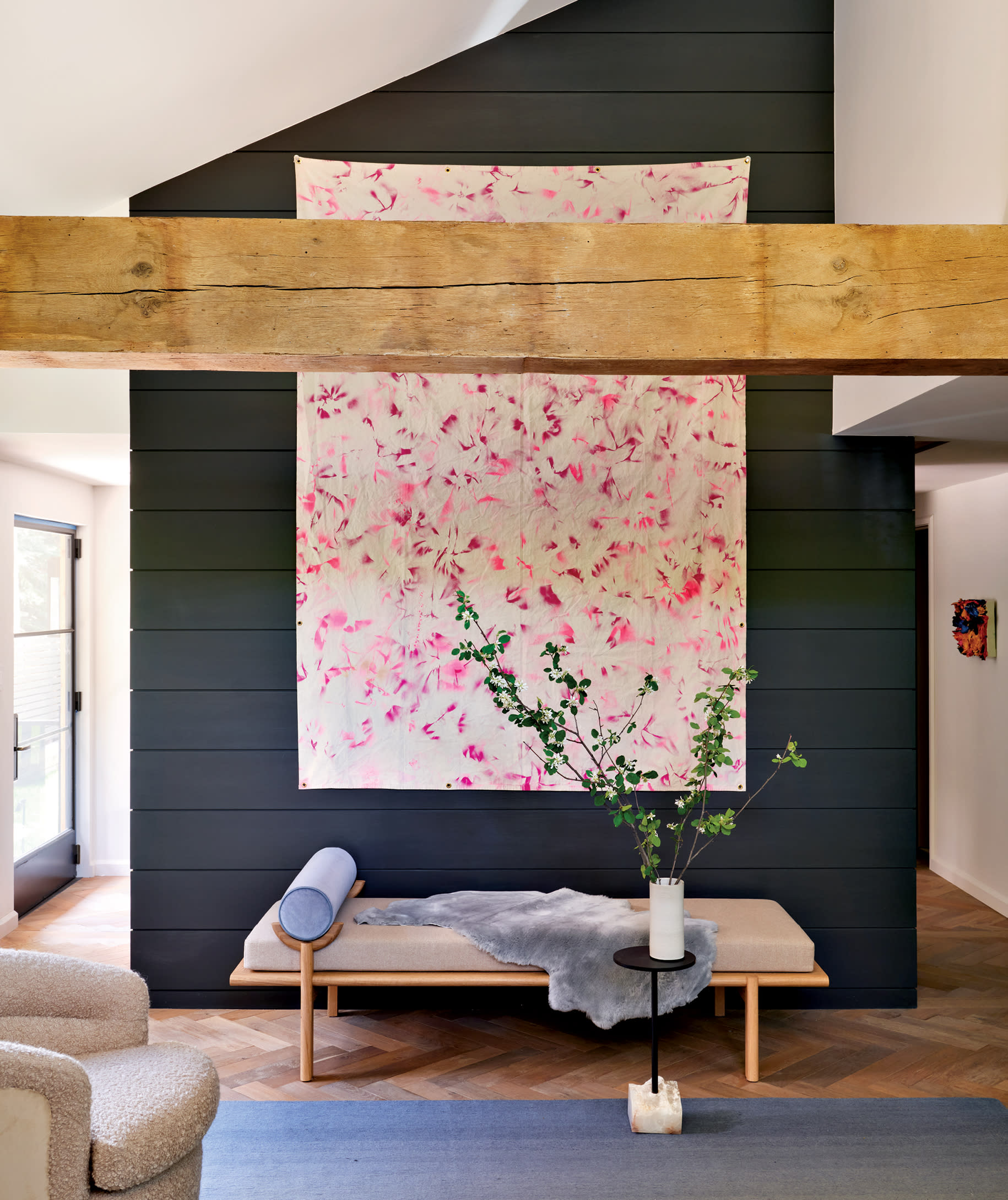 midcentury-inspired bench below a stairwell shaft with a black wall