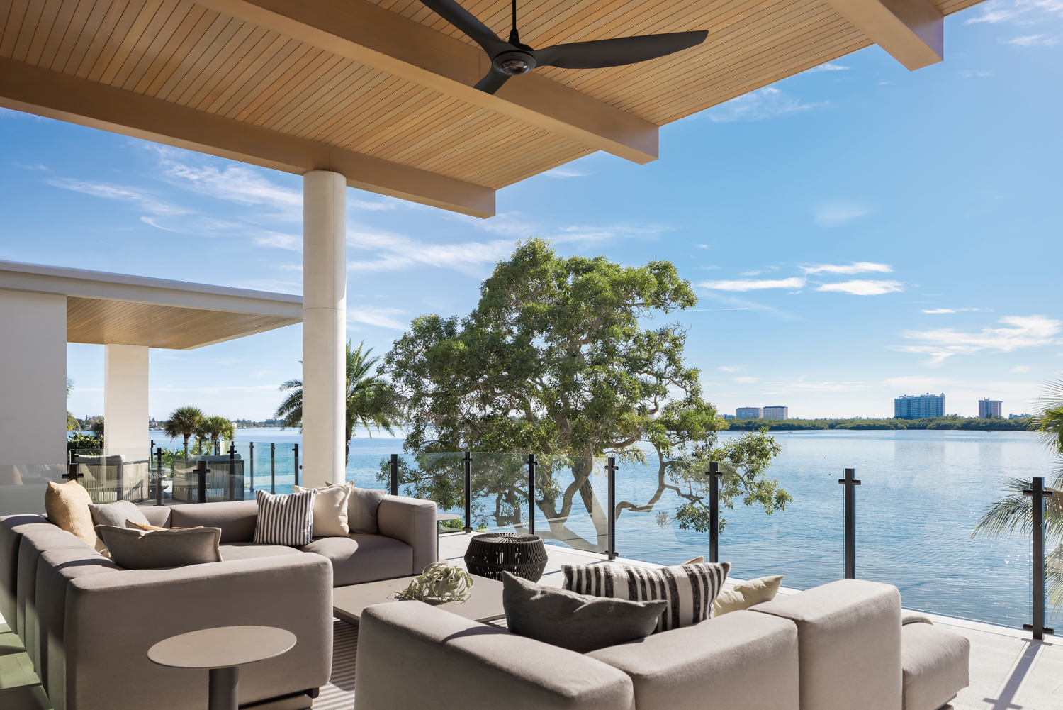 living area terrace with gray sectionals, coffee table and side tables overlooking waterway