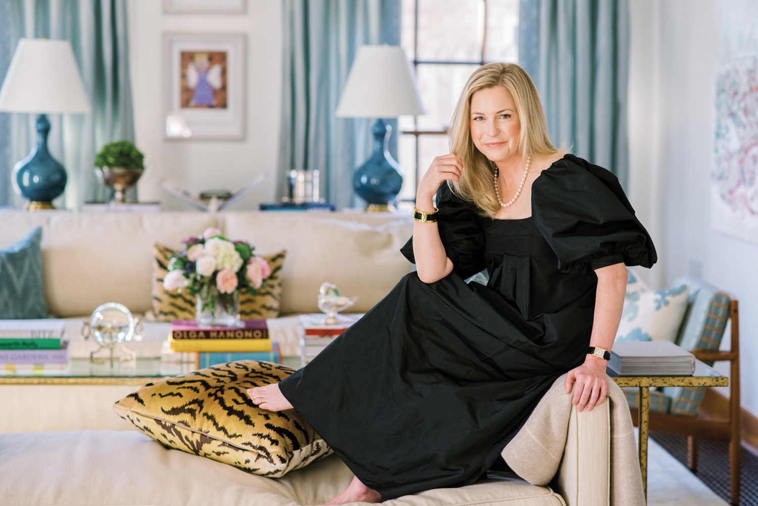 Christian Ladd portrait sitting on sofa arm in a living room vignette in a black dress