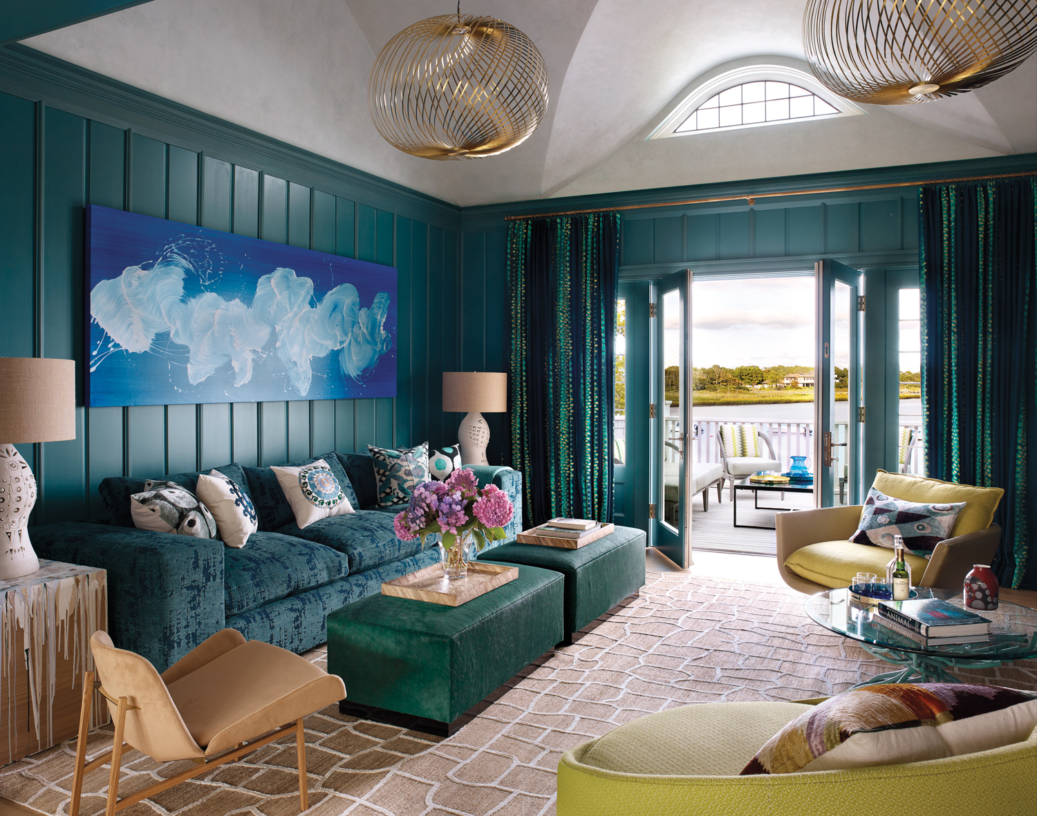 blue sitting room with blue couch, swirling artwork and doors opening up to the outdoor view by Ellen Hamilton