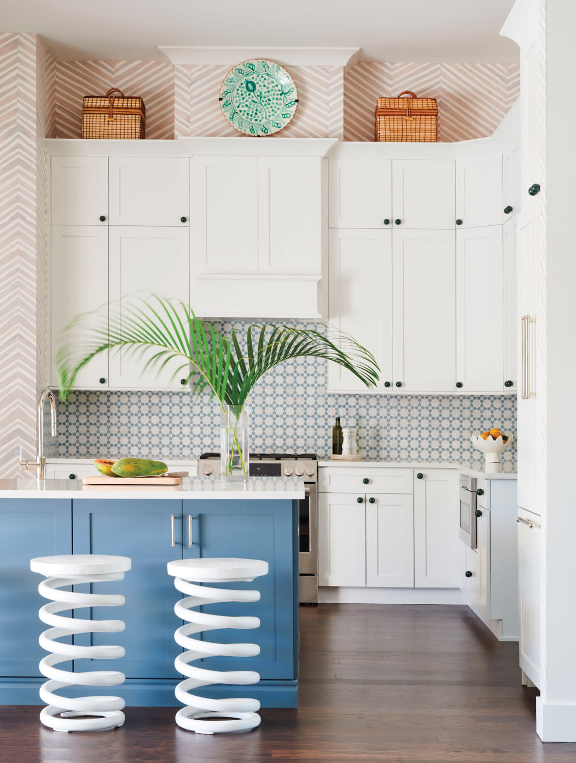 whimsical kitchen with white cabinetry, blue island and spring-shaped barstools