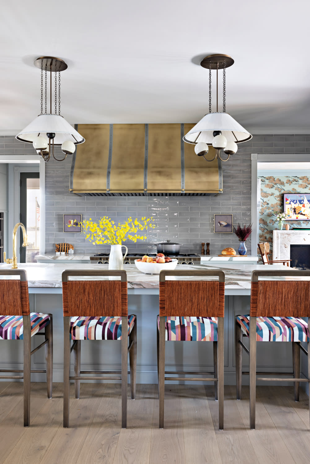 kitchen with gray-blue backsplash, stools with graphic patterned seats, and blue cabinetry