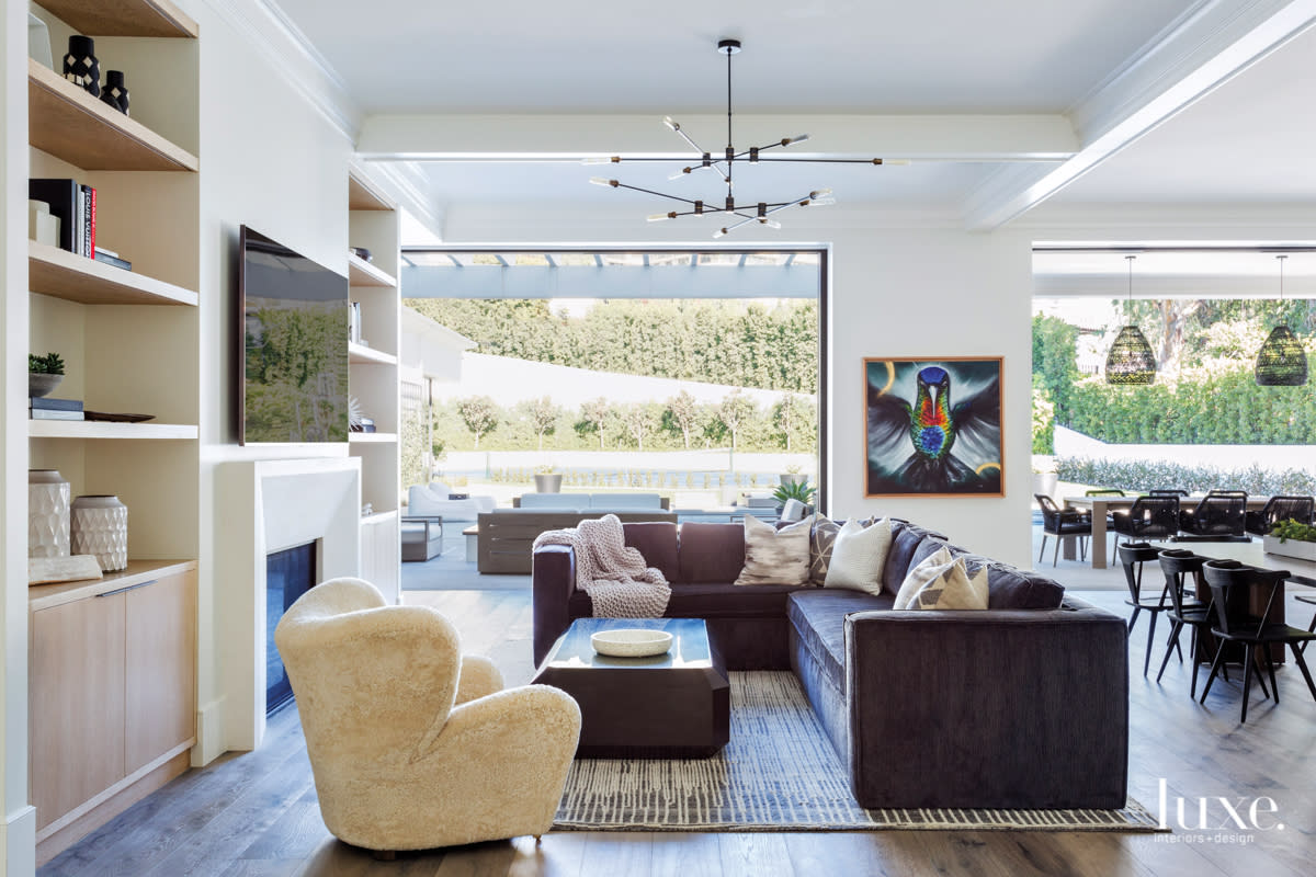 Webster notes the family room is the most popular spot in the house. A Stark rug anchors the space, where Webster placed a custom sofa from Pearce Upholstery, a Flemming Lassen chair from Horne and a Noir coffee table. The chandelier is by RH; the artwork is by THRY.