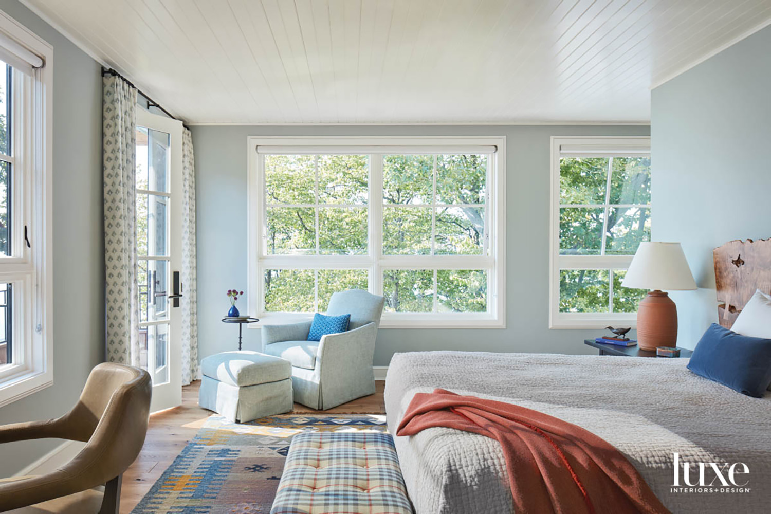 A light blue bedroom with a blue armchair and ottoman