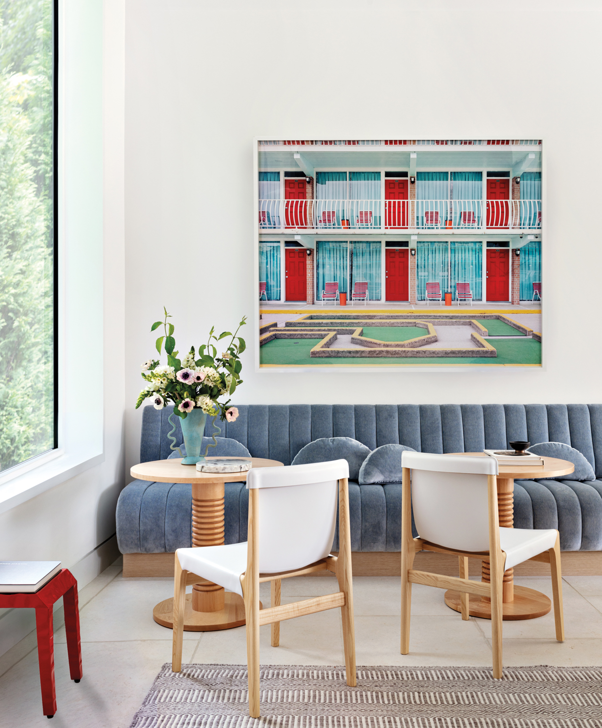 interior of a pool house with vivid artwork, white chairs and blue sofa