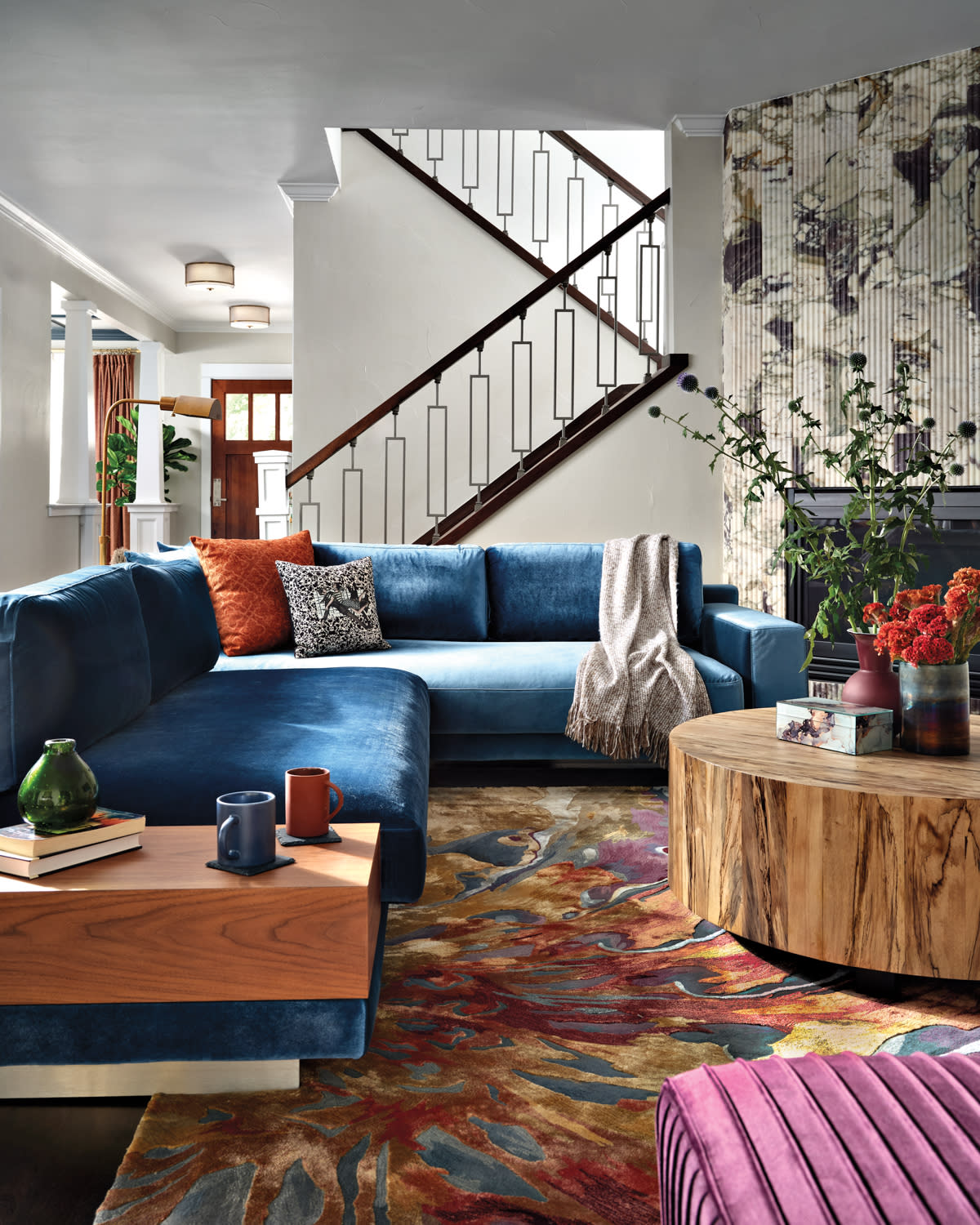 colorful living room with staircase in background and teal blue sectional