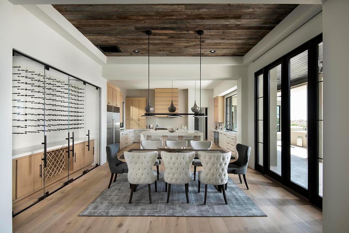 Dining room with tufted chairs, wine wall, rustic ceiling