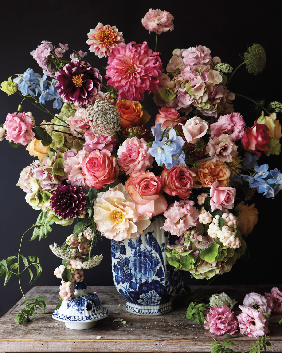 multiple colorful flowers in a blue and white vase on table