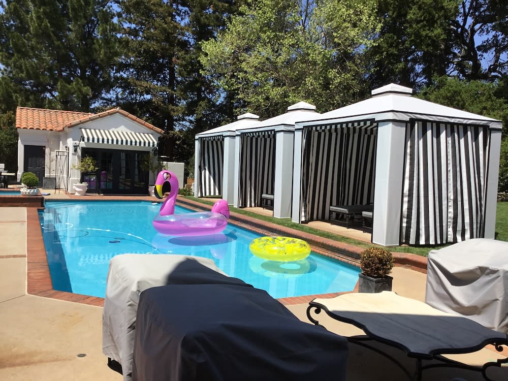 exterior of a California home with white cabanas and black-and-white stripe drapes