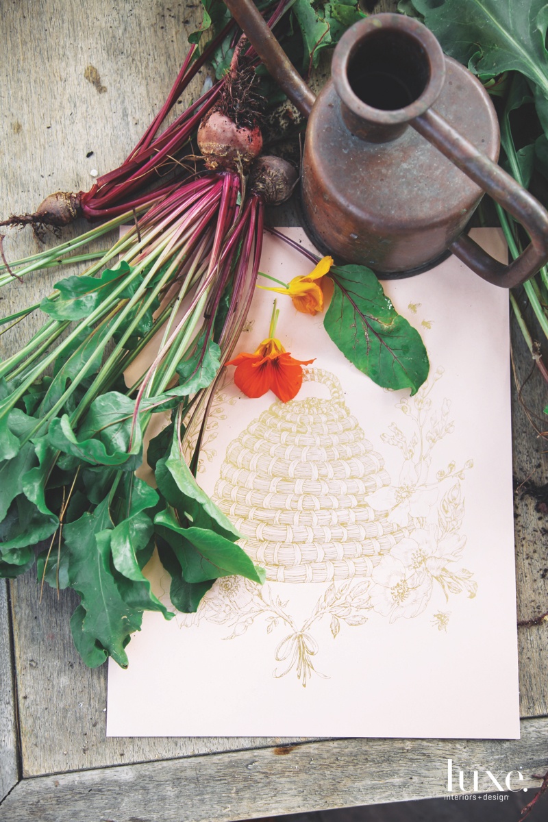 Beneath a bunch of fresh beets is a print of a bee skep, one of the botanical artworks that their design practice is known for.