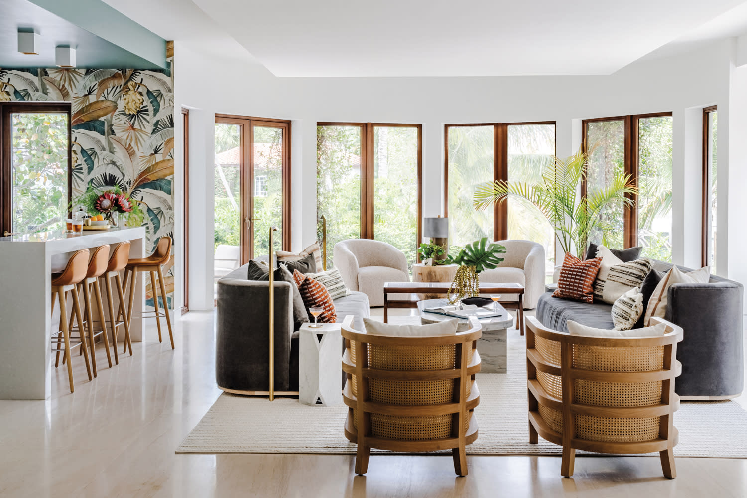 living area with barrel chairs, charcoal-colored sofa, white rug and curved window wall