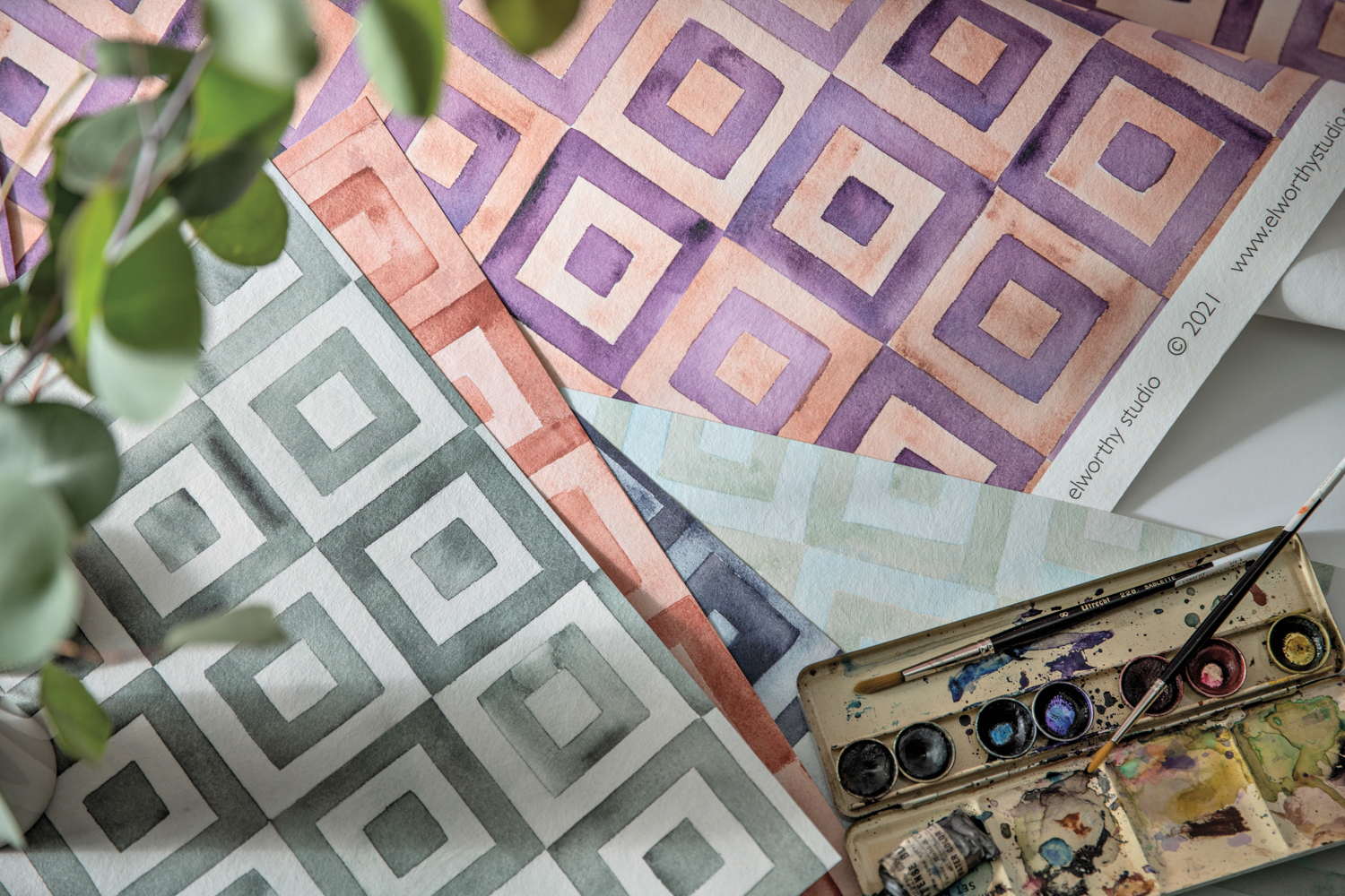 Samples of a geometric-patterned wallpaper in green, red and purple.