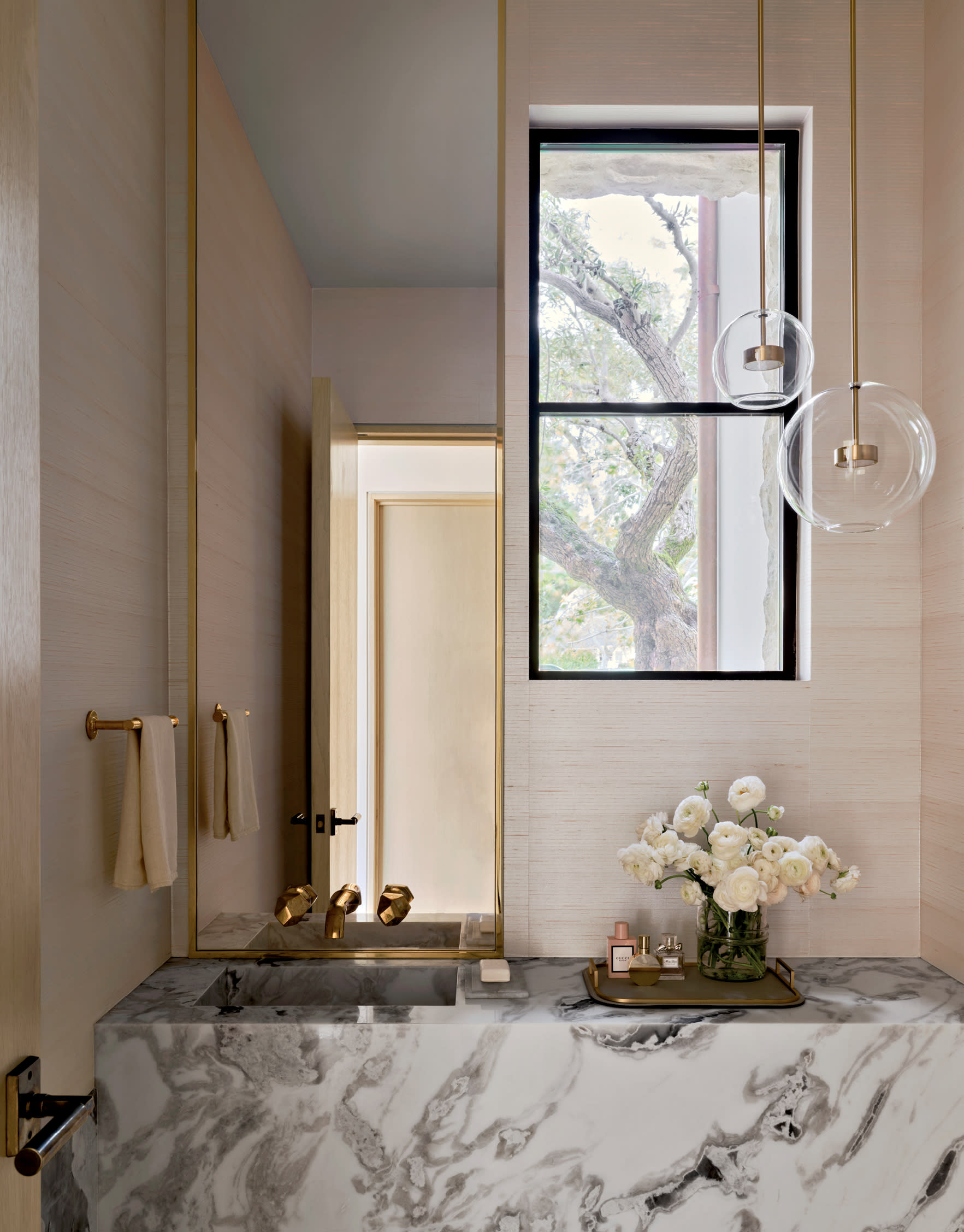 chic powder room with light pink walls, gray marble vanity and brass fixtures