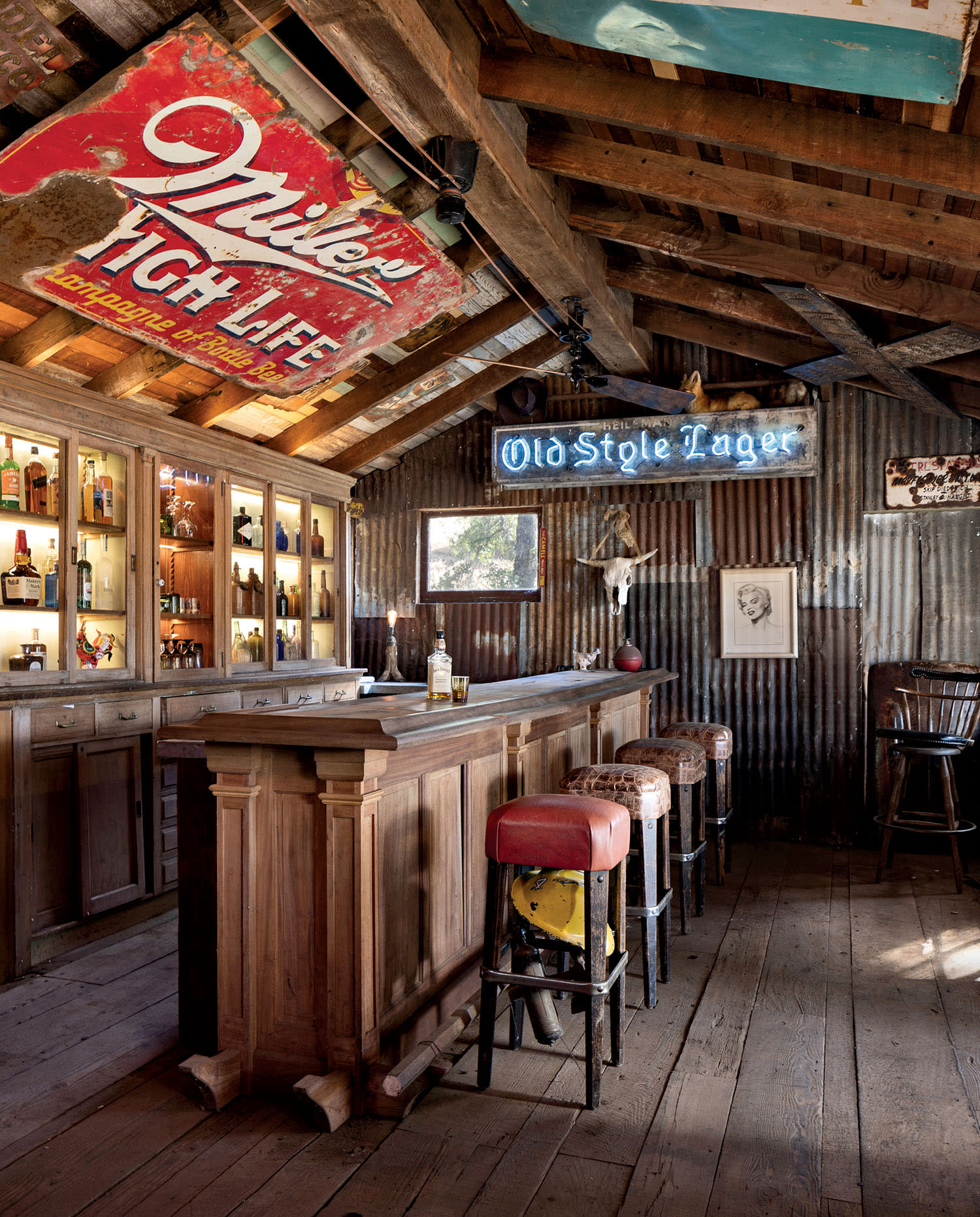 Rustic bar with wooden counters, vintage stools, corrugated metal walls, and retro signs. Bottle-filled shelves create a nostalgic, cozy atmosphere.