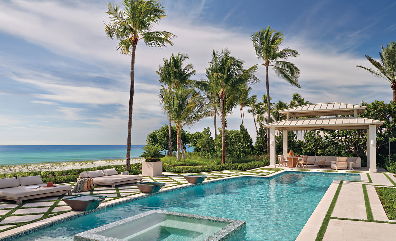Luxurious beachfront pool with clear blue water, surrounded by palm trees and modern lounge chairs