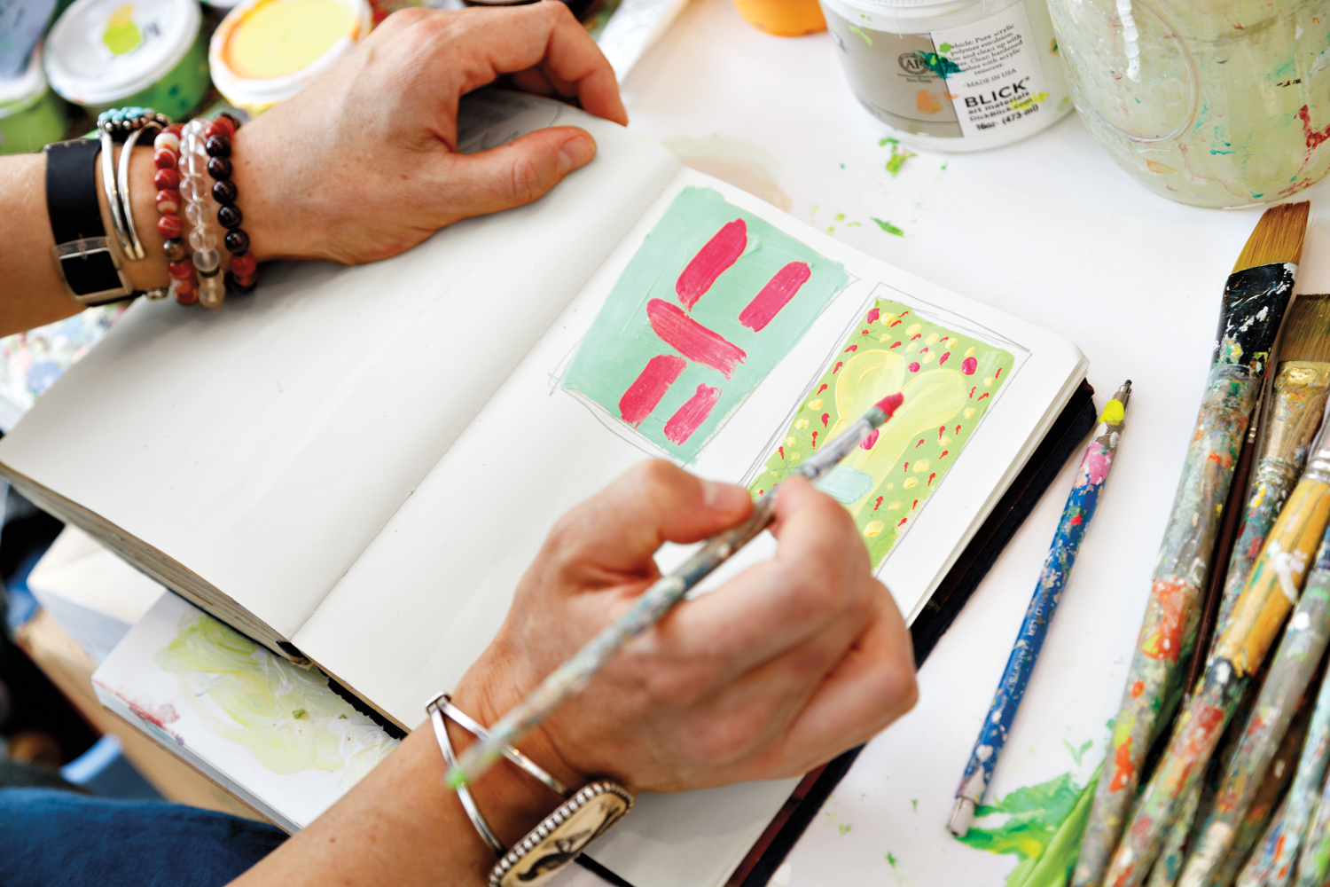 Woman at desk painting studies in small notebook