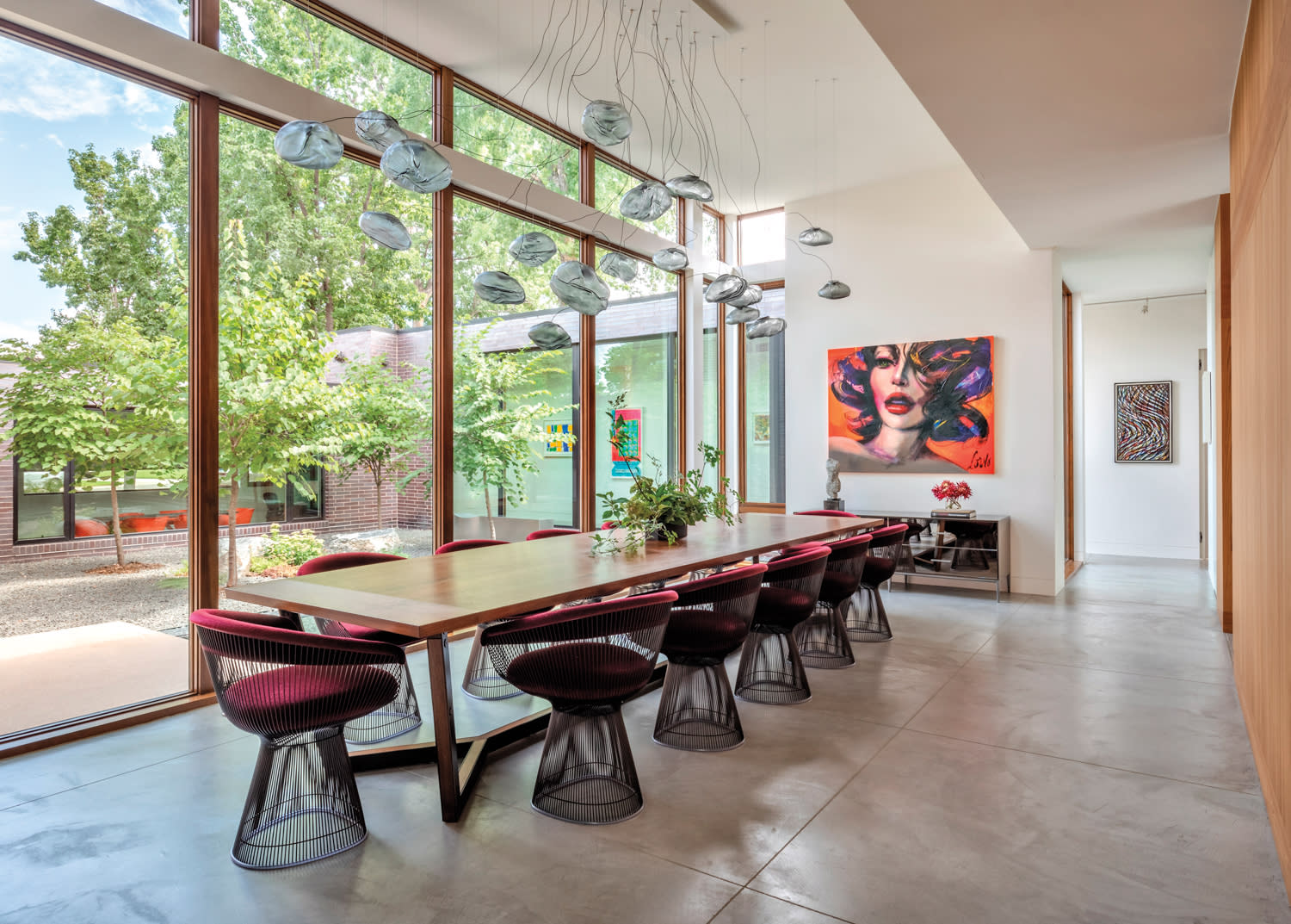 dining room with mesh stools, long dining table and floor-to-ceiling windows by Jessica Doran