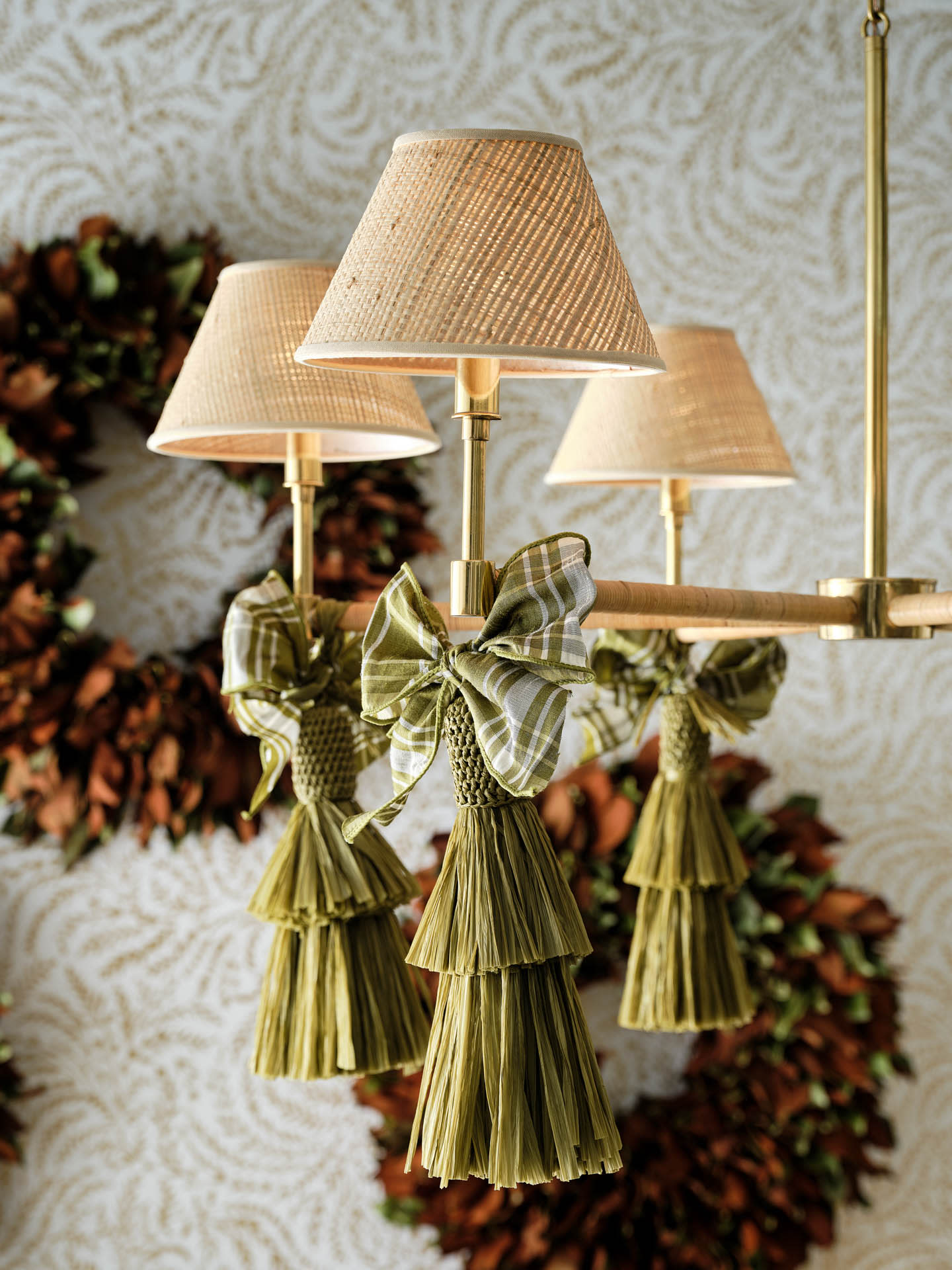 a trio of shaded sconces with green tassels in front of a couple of holiday wreaths