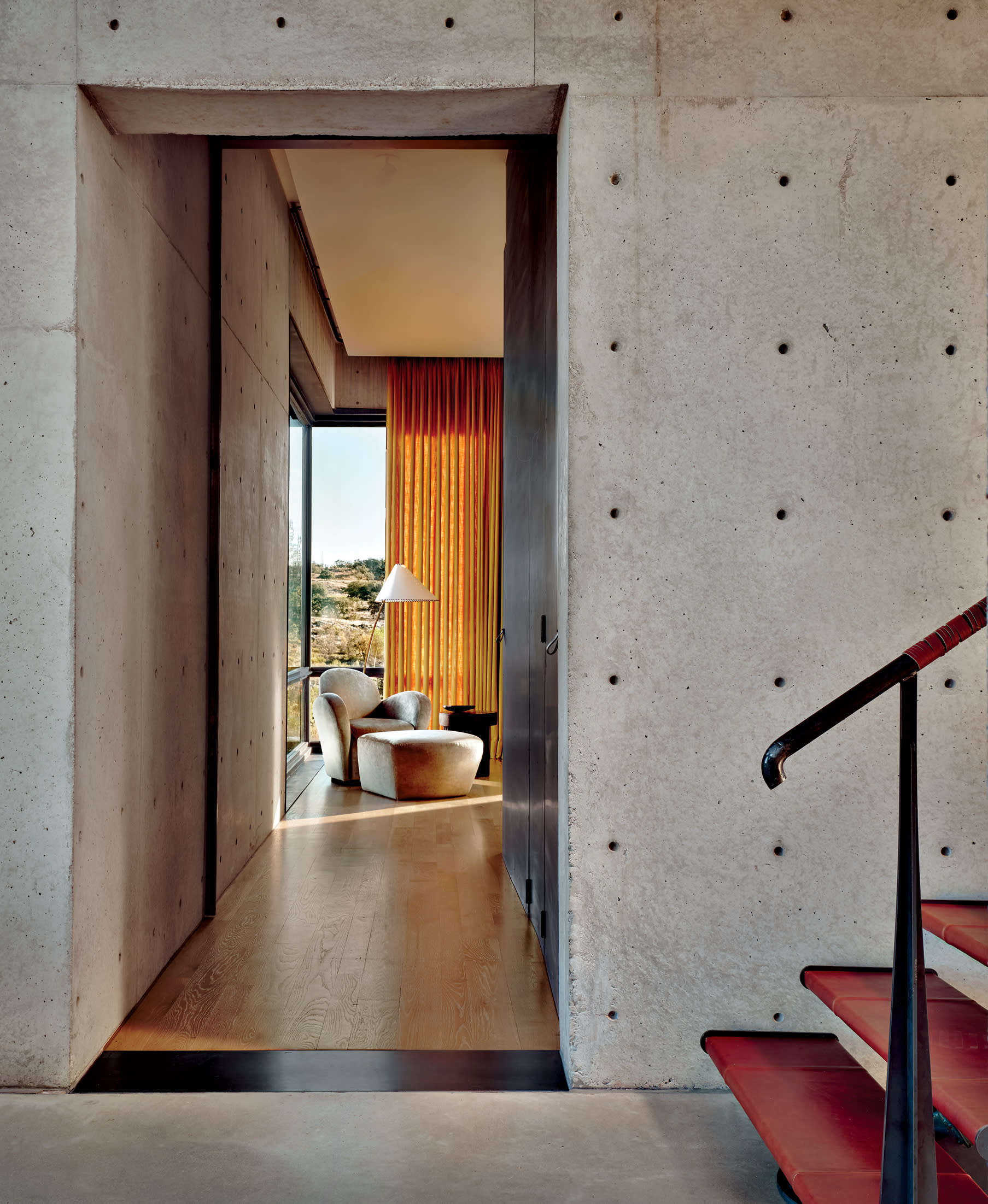 a cozy guest room vignette seen from the hallway of a Brutalist home