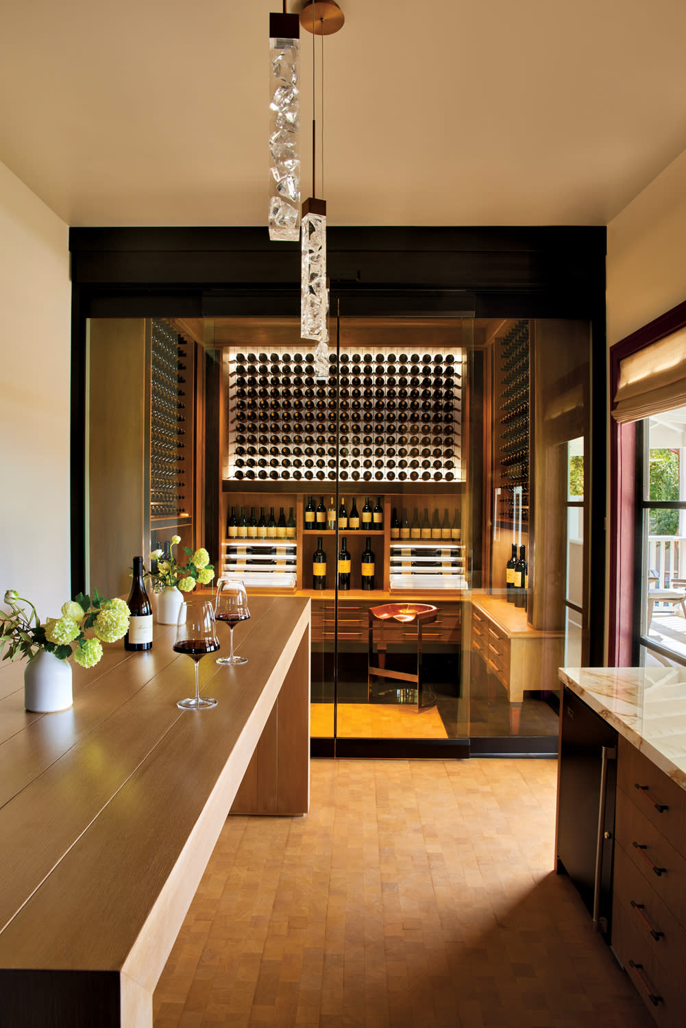 Glass-enclosed wine storage room behind a long wood table.